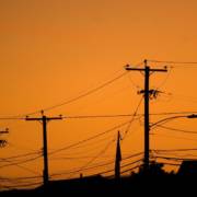 silhouettes of the power lines and wires in a residential neighborhood backlit by the evening sky HYu4Qv0ro